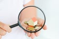 Real estate concept - coins and house architectural model in woman hand under magnifying glass Royalty Free Stock Photo