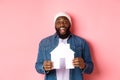 Real estate concept. Happy smiling african-american man holding house model, looking excited at camera, searching for Royalty Free Stock Photo