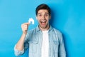 Real estate concept. Happy young man looking excited, found apartment, showing small house model, standing over blue Royalty Free Stock Photo