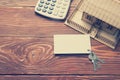 Real Estate Concept. Model house, keys, blank business card and calculator on wooden table. Top view. Toned image