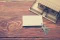 Real Estate Concept. Model house, keys, blank business card on wooden table. Top view. Toned image