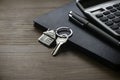 Real estate concept. Selective focus of key and house keychain, calculator, pen and notebook on wooden background Royalty Free Stock Photo