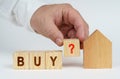 On a white surface there is a model of a house, next to it a man has placed cubes with the inscription - BUY Royalty Free Stock Photo