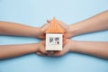 Real estate and eco concept - close up picture of human hands holding house on blue background Royalty Free Stock Photo