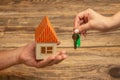 Real estate and eco concept - close up picture of human hands holding house on wooden background Royalty Free Stock Photo