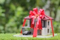 Real estate and Gift new home concept,Model house with Red ribbon and key on natural green background Royalty Free Stock Photo
