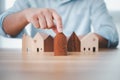 Real estate investment businessman hand choosing mini wood house model from model on wood table, Planning to buy property. concept