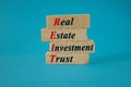 Real estate investment trust symbol. Concept red words Real estate investment trust on brick blocks on beautiful blue background.