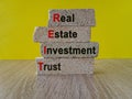 Real estate investment trust symbol. Concept red words Real estate investment trust on brick blocks on beautiful yellow background