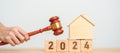 Real Estate Law, Home Insurance, property Tax, Auction and Bidding concepts. 2024 year block with small toy house model with gavel Royalty Free Stock Photo