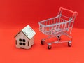 Real estate sales and realtor services. Buying a new home and housing, concept. A small model of a wooden house with a toy shoppin Royalty Free Stock Photo