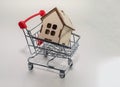 Real estate sales and realtor services. Buying a new home and housing, concept. A small model of a wooden house with a toy shoppin Royalty Free Stock Photo