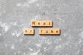 Real or fake word written on wood block. Real or fake text on cement table for your desing, Top view concept Royalty Free Stock Photo