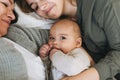 Real family of young mom and two kids of different ages teenager girl and baby boy having fun on the bed