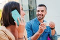 Real handsome man drinking a coffee cup and looking to his girlfriend, she is having a call by phone. Young caucasian Royalty Free Stock Photo