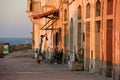 Real life on Malta sea side during orange sunset - boy hanging clothes drying, two washing machines and gignger cat