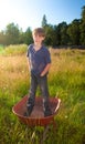 A real life young boy standing in a wheelbarrow