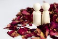 Real love, lover, couple concept. Two wooden figures with red rose petals on white background, standing together