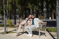 Real marriage of gay couple, holding hands, heads together and eyes closed, sitting on a wooden bench, complicit and happy. Royalty Free Stock Photo