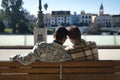 Real marriage of gay couple, holding hands, heads together and eyes closed, sitting on a wooden bench, complicit and happy, seen