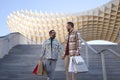 Real marriage of gay couple, holding hands, walking down some stairs and with many shopping bags in the other hand, happy and Royalty Free Stock Photo