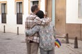 Real marriage of gay couple, hugging on the street, with a gay pride flag in their pocket and seen from the back. Concept lgtb,