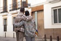 Real marriage of gay couple, hugging on the street, with a gay pride flag in their pocket and seen from the back. Concept lgtb,