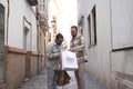 Real marriage of gay couple, in a lonely street, with their hands full of shopping bags, while one shows the shopping to the other