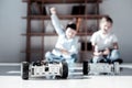 Overjoyed kids racing while playing with robotic vehicles Royalty Free Stock Photo