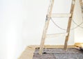 Real old wooden ladder of a painter in use for an interior renovation. Painter cover fleece for protection of floor surfaces. Royalty Free Stock Photo