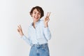 Real people. Happy young caucasian woman dancing with eyes closed, having fun, showing peace sign and smiling, standing Royalty Free Stock Photo