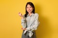 Real people portraits. Happy young Asian woman with dark hair looking at camera and smiling over yellow background