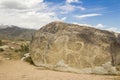 Real petroglyphs on natural stone found in the steppe, on a blurred background of beautiful mountains