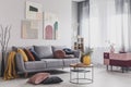 Abstract paintings hanging on white wall above a gray sofa in a living room interior with big windows Royalty Free Stock Photo