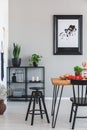 Real photo of black stool and shelf with plants in a dining room interior