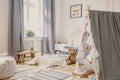 Real photo of a blue kid room interior with mattress, curtains, teddy bear and tent where a boy is reading a book Royalty Free Stock Photo