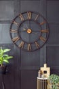 Real photo with close-up of big clock hanging on black wall in d
