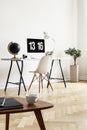 Real photo of a coffee table with notebooks and cup with a desk, globe, computer and chair in the background in a home office inte Royalty Free Stock Photo