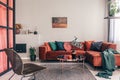 photo of a comfy living room interior with a round table on gray rug, wicker armchair and red corner sofa Royalty Free Stock Photo