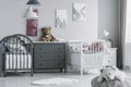 Real photo of a cute, white teddy bear on a pouf in a bright kid bedroom interior with twin beds Royalty Free Stock Photo