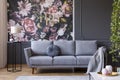 Real photo of dark living room interior with glass lamp, floral