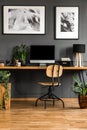 Real photo of a dark, wooden home office interior with empty com Royalty Free Stock Photo