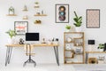 Real photo of a desk with a computer screen, ornaments and a plant standing with a chair next to shelves with more ornaments and Royalty Free Stock Photo