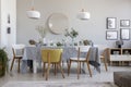 Elegant dining room interior with a laid table, chairs, mirror on a wall and lamps Royalty Free Stock Photo