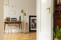 Real photo of an elegant home office interior with golden accents. View through opened door