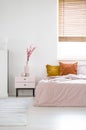 Real photo of a feminine bedroom interior with pink sheets on a