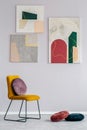 Gray living room interior with a set of modern paintings on the wall and a velvet cushion on a yellow chair Royalty Free Stock Photo