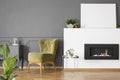 Real photo of a green armchair standing next to a bio fireplace Royalty Free Stock Photo