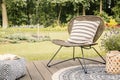 Real photo of a modern garden chair with a white, striped pillow