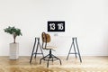 Real photo of a modern home office interior with a computer, desk and chair. Empty wall, place your poster